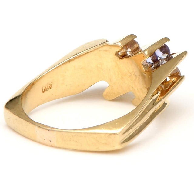 Yellow gold bars hold brilliant diamonds and violet tanzanites, each cut in an elegant round shape. With fabric-like...