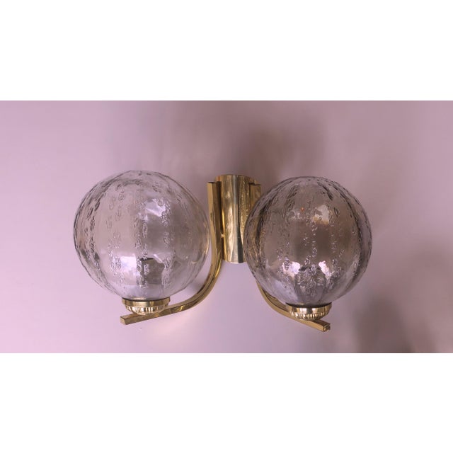 A pair of double-wall lights from the 1970s, each with two globes in structured glass on a brass frame. Up to 250V...