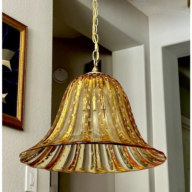 Murano Italian bell shape gold amber colored hand blown glass pendant ceiling light. The glass has vertical ribbing along...
