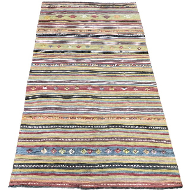 A beautiful vintage kilim, handwoven in central Turkey circa 1960 featuring a traditional, multicoloured banded design in...