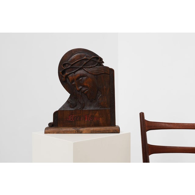 A deeply expressive hand‑carved wooden relief depicting the head of Christ crowned with thorns, inscribed Ecce Homo...