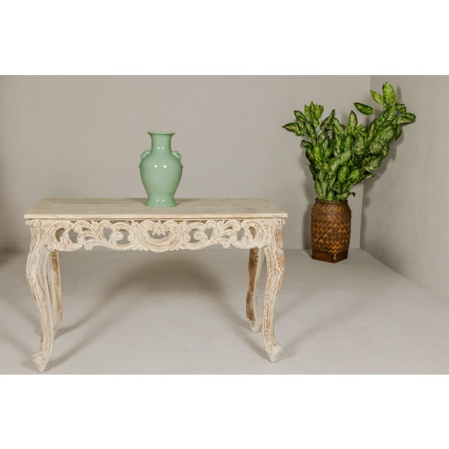 A Rococo style console table with distressed painted finish, carved apron, cabriole legs and scrolling feet. We have two...
