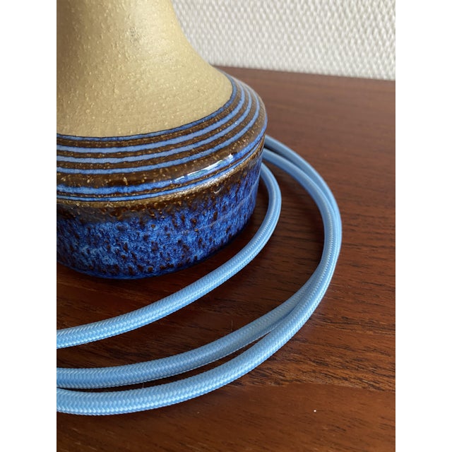 This handcrafted stoneware table lamp captivates with its shimmering, elegant blue glaze. In very good condition, it bears...