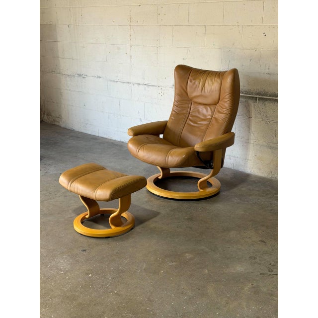 This Stressless recliner and matching ottoman feature an ergonomic high-back design with smooth swivel function. A curved...