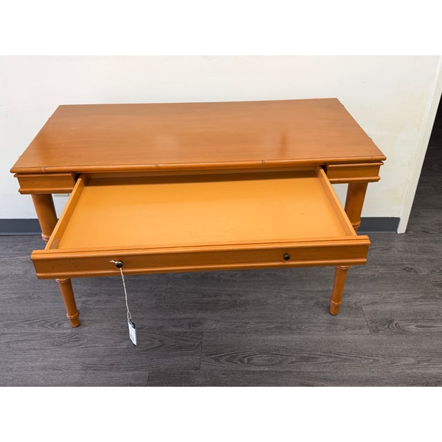 Beautiful vintage wooden writing desk featuring a warm honey-toned finish, two front drawers, and elegant turned legs. A...