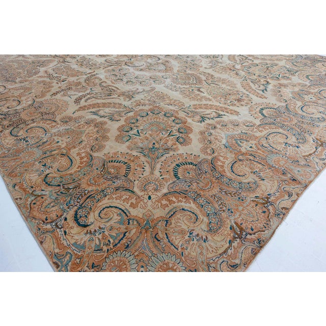 An early 20th century Persian Kirman carpet, the camel field with a symmetrical design of elaborate flowering branches...