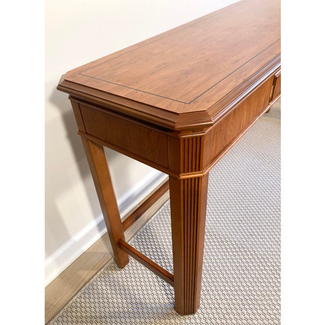 This classic console table for Drexel Heritage features a warm fruitwood finish, classic fluted pillar legs, and a subtle...