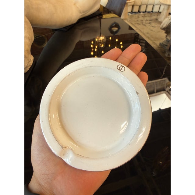 A vintage Gucci ceramic ashtray crafted in Italy, featuring a clean, minimalist design in glossy white ceramic accented by...