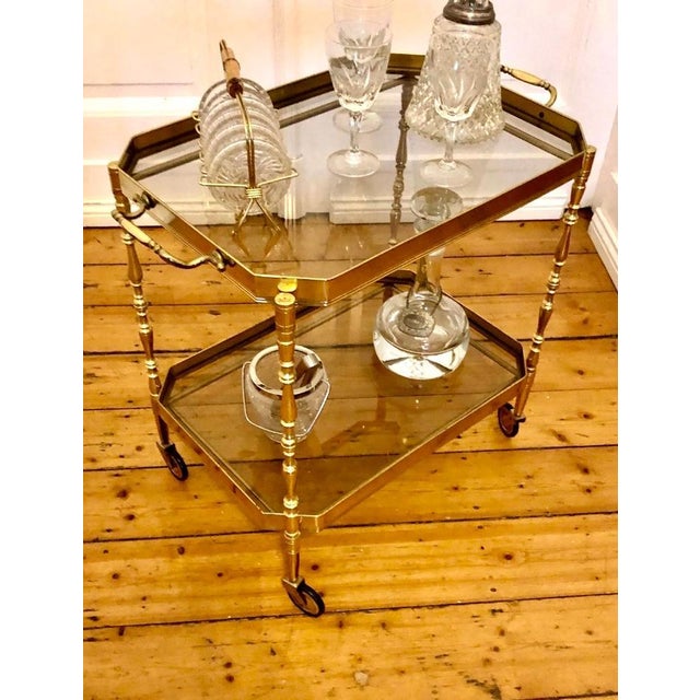 Elegant brass serving trolley from the beautiful old era, featuring two removable dark crystal glass trays on casters, in...