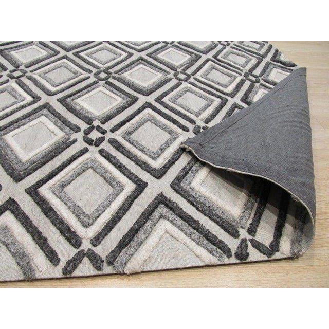 This gray wool rug features a hand knotted pile construction, offering a durable floor covering option for residential...