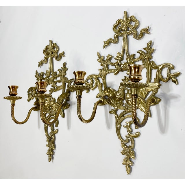 Pair of vintage Hollywood Regency style brass sconces depicting love birds on floral branch. Ribbon topper with intricate...