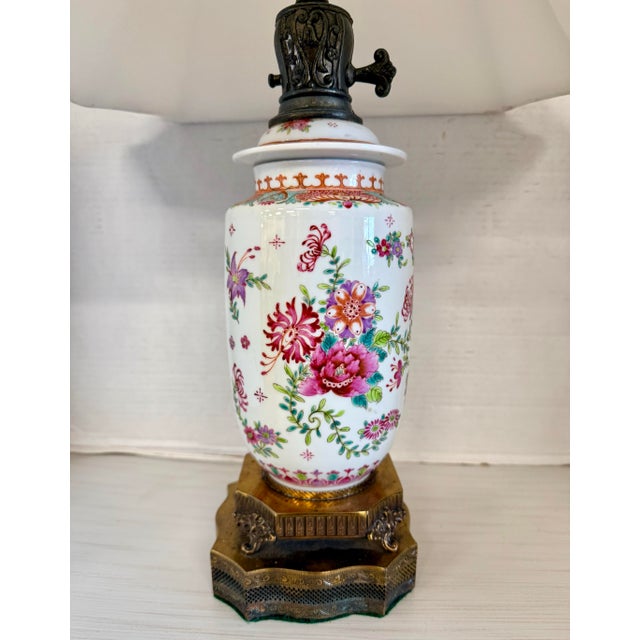 Elegant Chinoiserie-style porcelain lamp featuring colorful floral decoration with red and gilt accents. Set on an ornate...