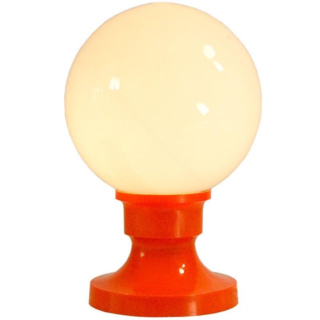 A small table lamp designed in the Space Age style. It is made of light orange plastic. Ball lampshade made of milky...