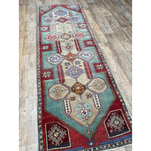 A lovely vintage Turkish Oushak runner rug. This vintage Oushak runner offers a red palette with green, blue, and tan...