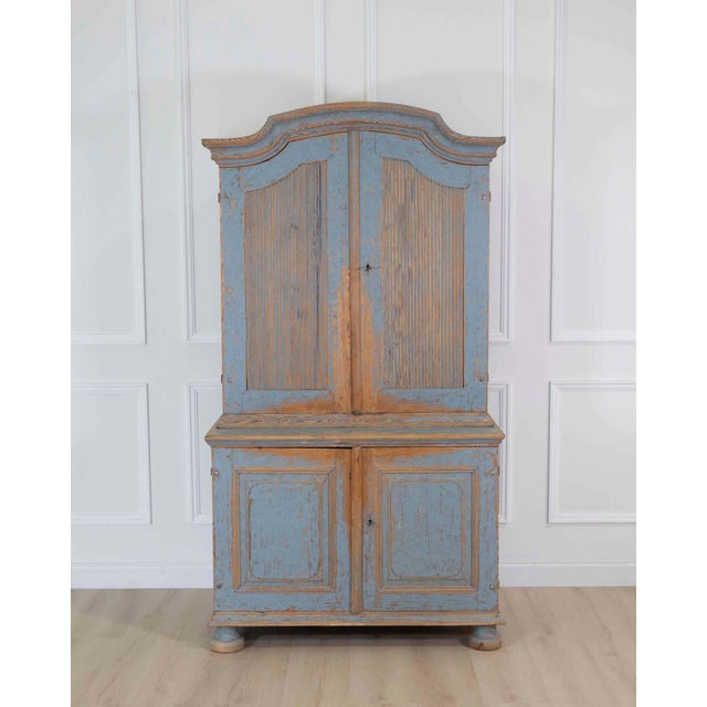 A beautiful early 19th century Rococo cabinet featuring elegant reeded top doors and a softly repainted finish in muted...