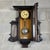 A refined and dramatic wooden pendulum wall clock with a glass door, fluted columns, and two beveled side mirrors, a...