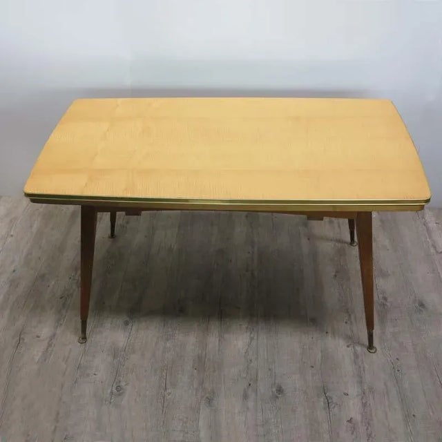 This 1950s vintage wooden table is extendable on the long sides and sits on four feet.