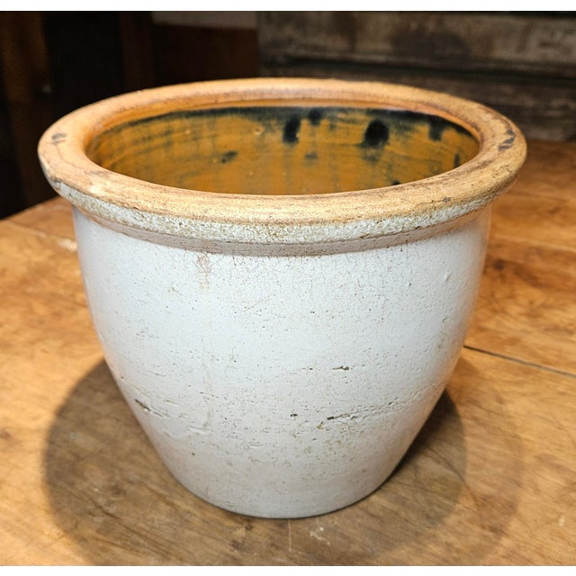 Antique salt-glazed stoneware crock featuring the distinctive crackle or orange peel texture created by the salt glazing...