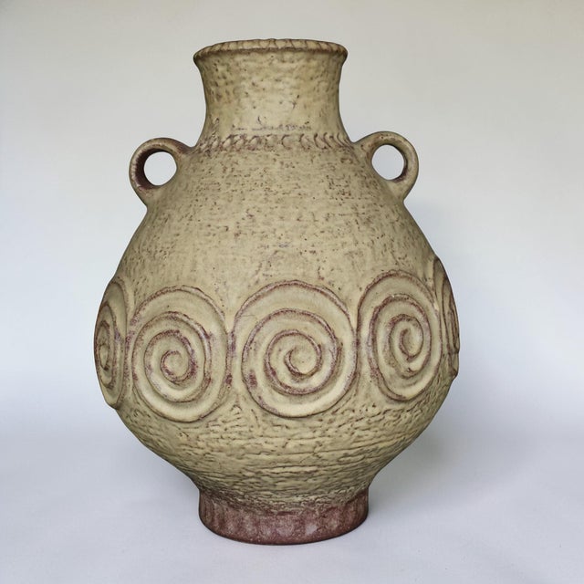A large West German ceramic amphora vase dating to the 1970s, featuring a warm sand-toned glaze and a band of raised...