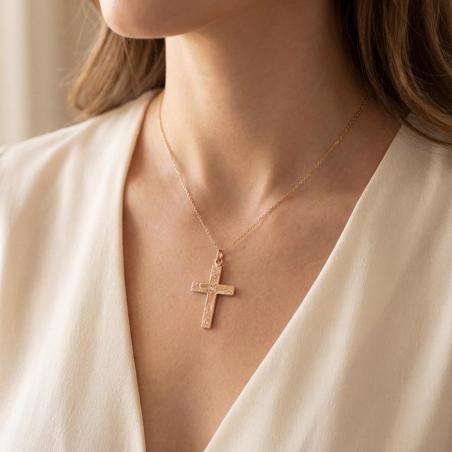 A Victorian detailed 9k rose gold cross pendant. Features intricate engravings and a central brilliant-cut diamond. The...