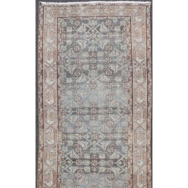 This antique Persian Hamadan rug has been hand-knotted in wool and features an all-over sub-geometric design rendered in...