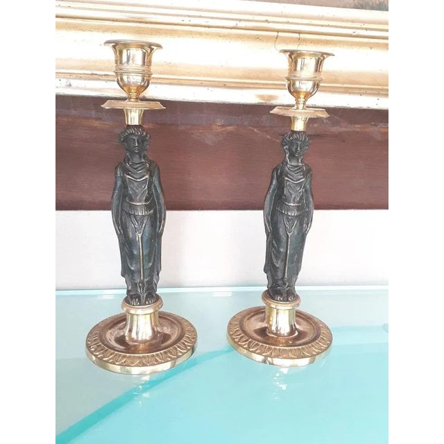 Two Empire candlesticks in natural bronze and 18 kt gilded bronze of beautiful quality, original gilding has only been...