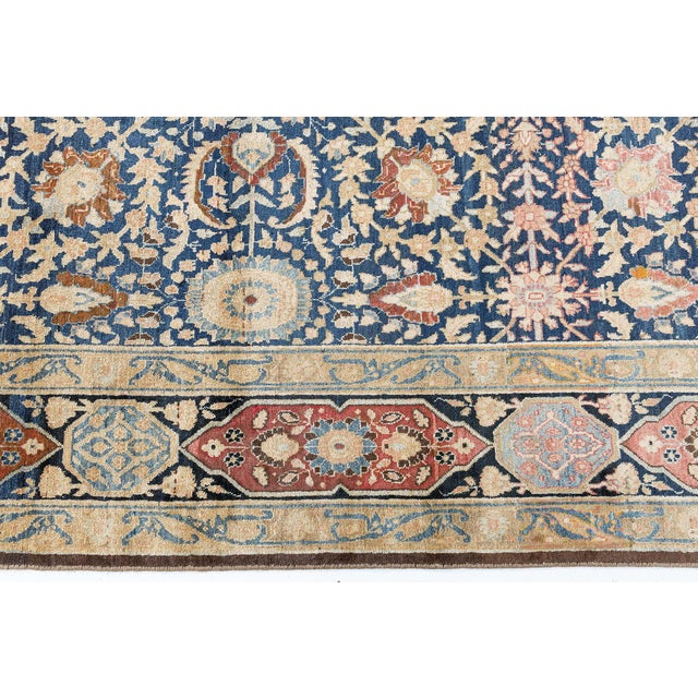 An early 20th century antique Persian Tabriz rug, the midnight blue field with a palmette, rosette, flowering vine trellis...