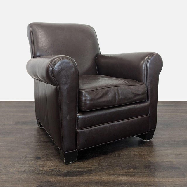 This lounge chair features a timeless design with dark brown leather upholstery and comfy rolled arms. The seat and...