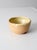 This vintage handmade studio pottery bowl features a rounded form with a warm tan glaze and soft cream glaze along the rim...