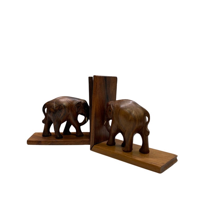 Charming pair of vintage wooden bookends featuring hand-carved elephants mounted on rectangular wood bases. Each elephant...