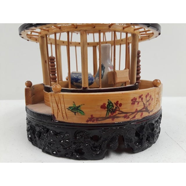 Vintage cricket cage with two blue porcelain water/food dishes. Has a carved black base below Asian handpainted letters,...