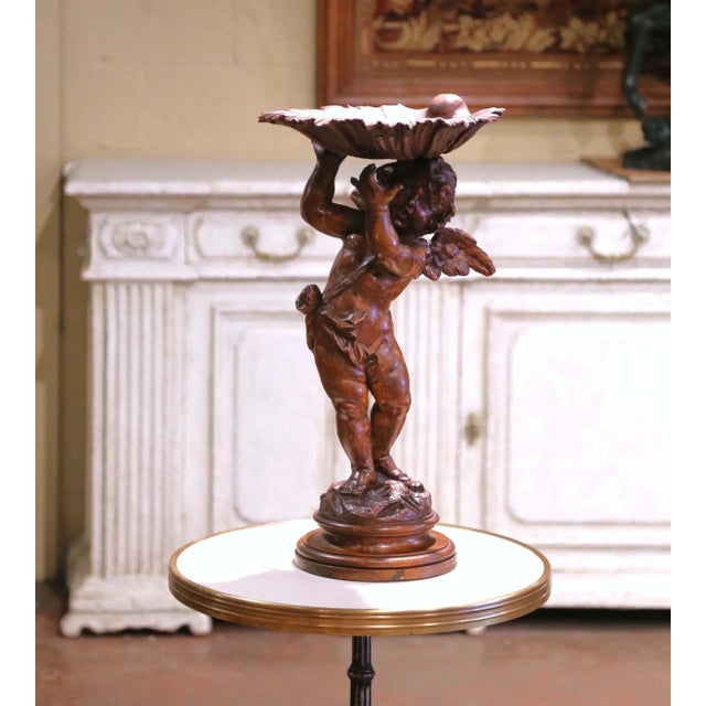 Carved in Italy circa 1870, this finely detailed 19th-century figural compote features a playful winged cherub supporting...