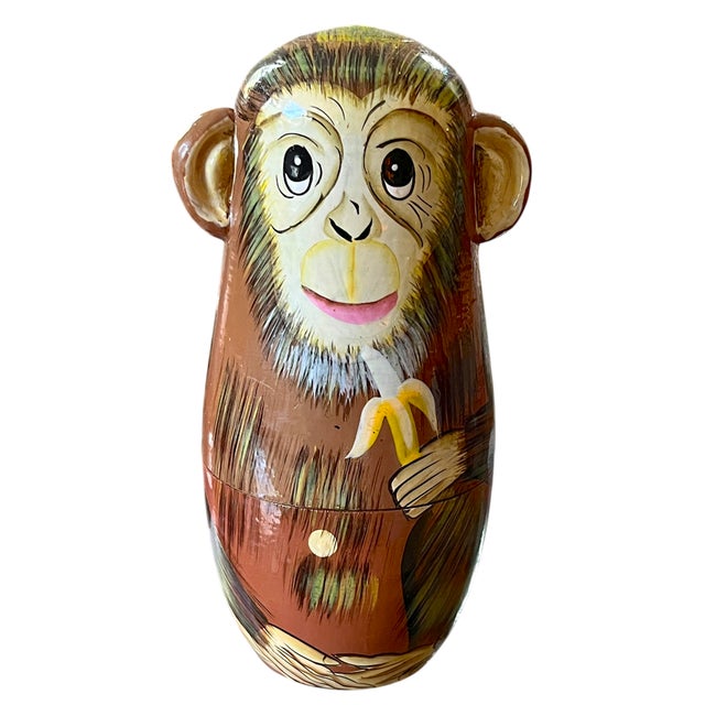 Four hand-painted wooden monkeys form a playful take on the traditional nesting doll. The largest, a wide-eyed brown...