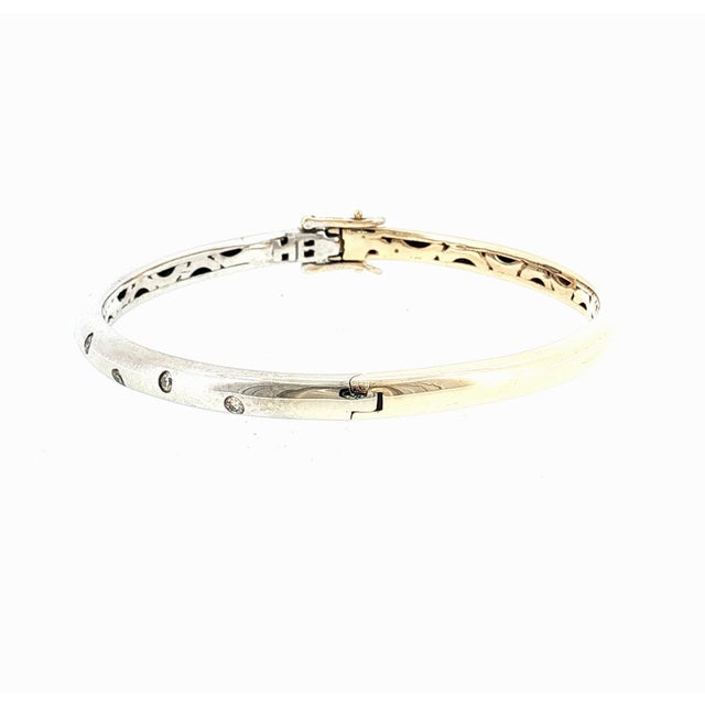 A contemporary 14k gold diamond hinged bangle bracelet. This piece features 10 brilliant-cut white diamonds with a total...