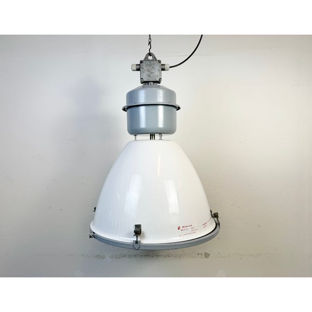 This industrial pendant light was made by elektrosvit in slovakia during the 1990s. It features a white enamel shade, a...