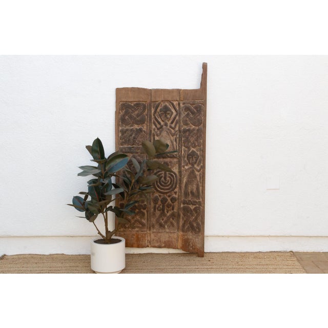 Look at this door long enough and it starts to read like a diagram: two guardian figures with their arms thrown open,...