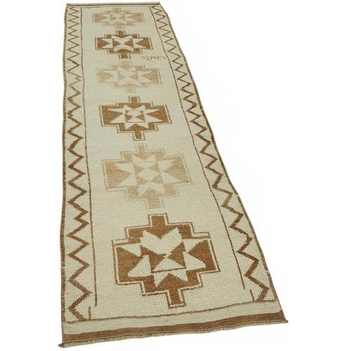 This exquisite runner rug is a rare example of tribal craftsmanship, hand-knotted by the women of the Herki tribe during...