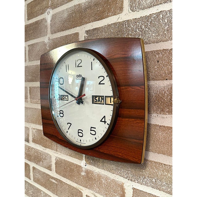 Rare vintage wall clock made in France by ODO, featuring a geometric design and a rectangular case with a wood-effect...