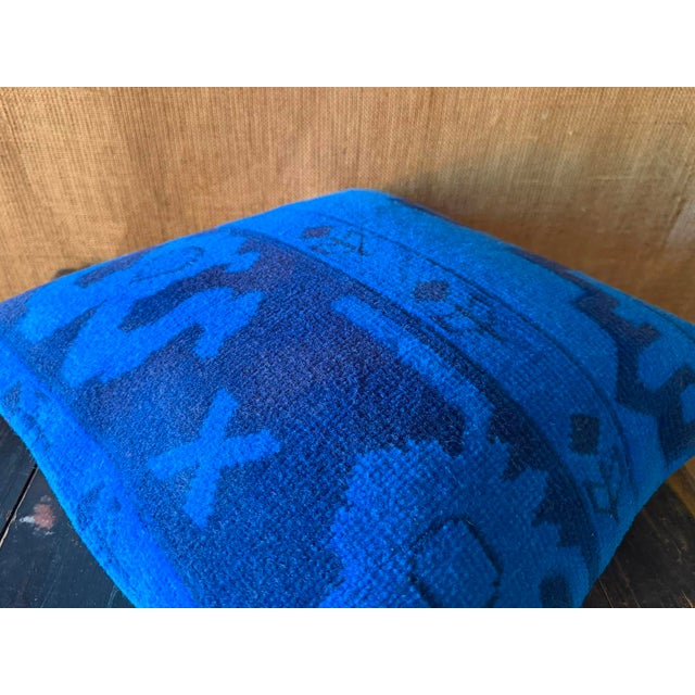 A sinuous navy motif coils across one side of the electric blue ground, its curling silhouette suggesting a stylized...