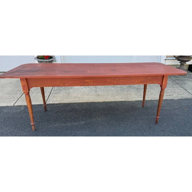 Nice good sized rustic farm table in old red paint. The legs of the table are from an early 19th century antique American...