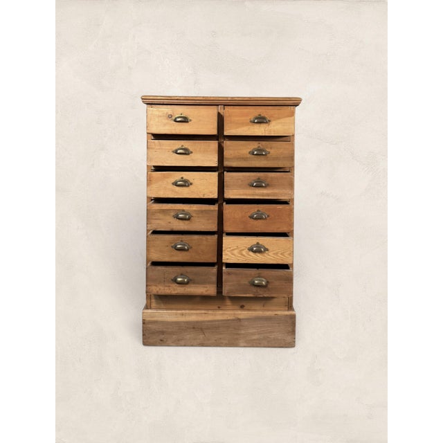 A charming antique pine multi-drawer cabinet, circa 1900, with twelve small drawers, warm aged patina, and classic brass...