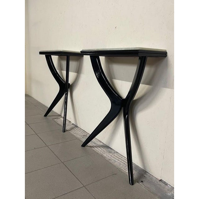 A pair of 1950s Italian-made console tables, also sold separately. The "X"-shaped structure is made of ebonized wood and...