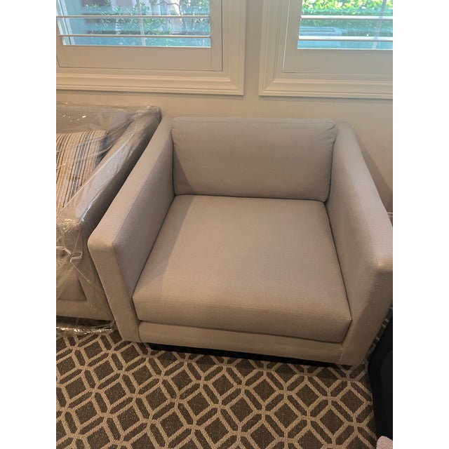 Wood frame, newly upholstered in Fresca Dove fabric. Loose cushions on seat and back. Track arm. Wood (black) inset base...
