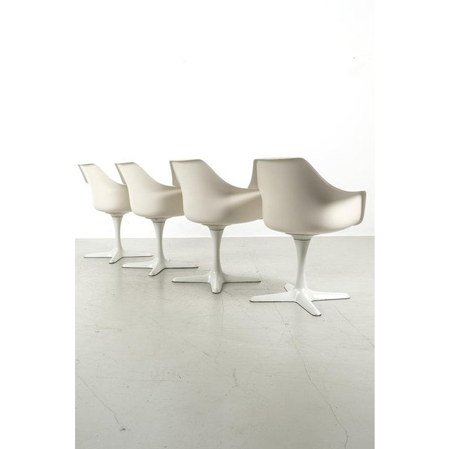 Set of 4 rotatable dining chairs with armrests and black upholstery. The chairs are designed by maurice burke for arkana....