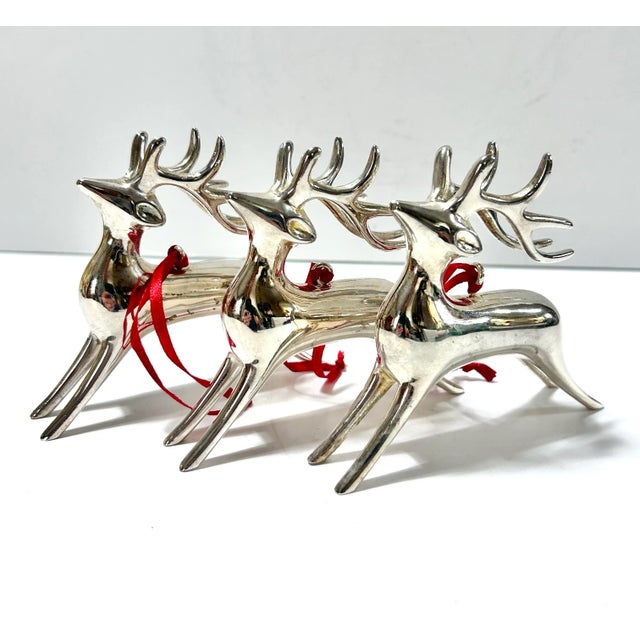Set of three vintage 1990s silver-plated reindeer Christmas ornaments with sleek stylized bodies, sculptural antlers and...