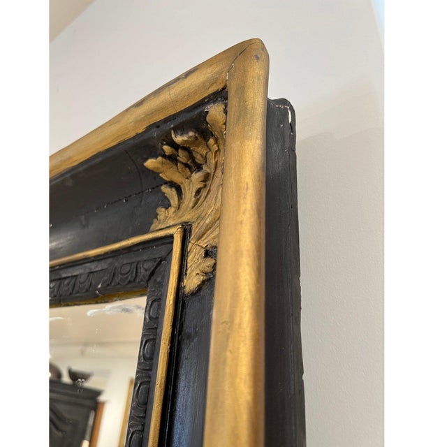 A dramatic 19th century French Napoleon III floor mirror featuring a striking black and gilt frame with rich contrast and...