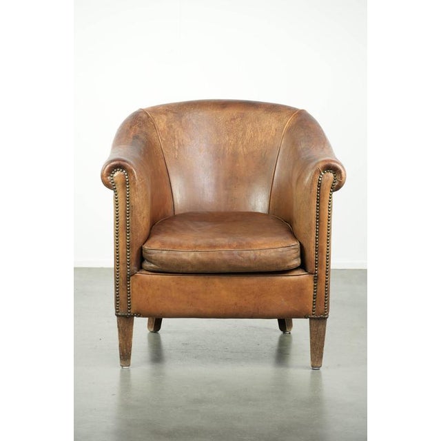This vintage sheepskin club armchair has an elegant appearance and is finished with decorative nails. The armchair...