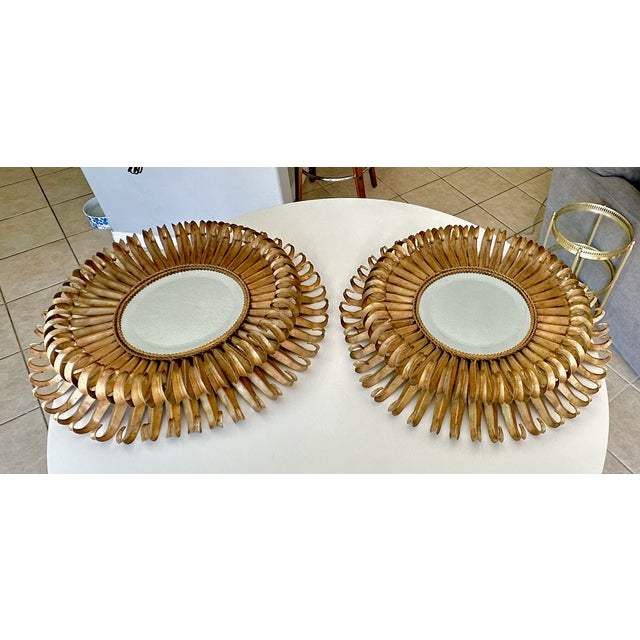 Pair of French style "eyelash" or sunburst style gilt metal tole wall mirror. The design features curved metal spokes...