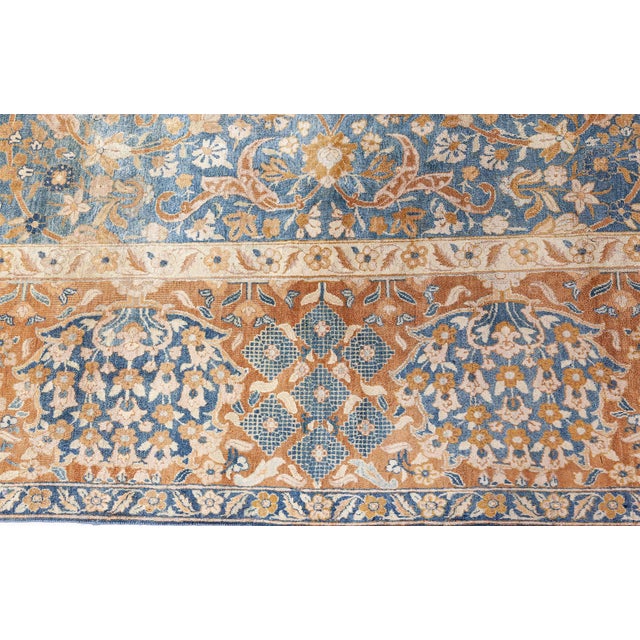 This late 19th century blue Persian rug features an intricate all-over design of ochre split leaves, flowers, and leafy...