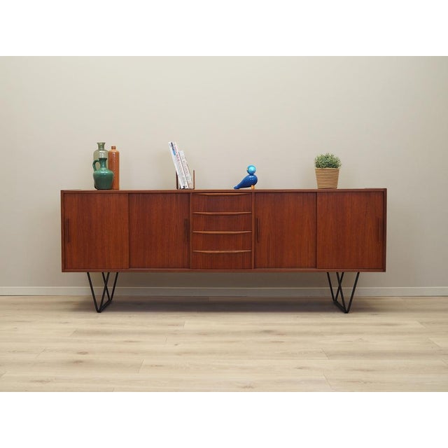The sideboard was made in the 1970s, Danish production. The structure is covered with teak veneer. Legs made of metal...